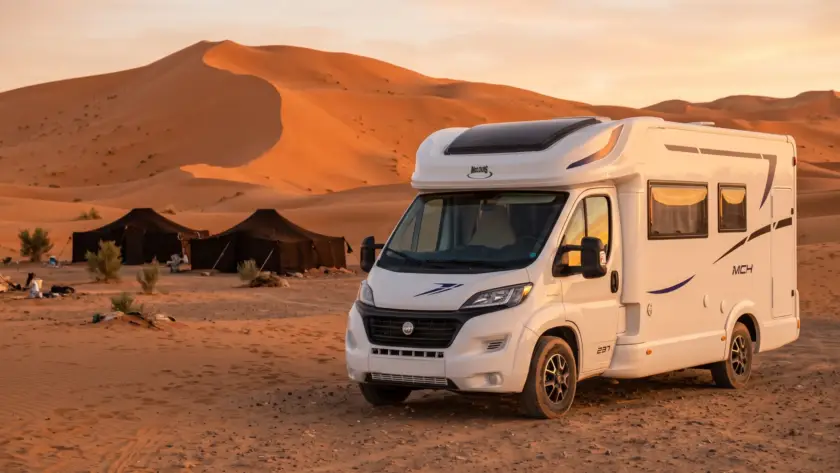 Nomade 4-person McLouis MC4 camper parked by Berber tents at the Erg Chebbi dunes near Merzouga, Morocco, at sunset